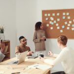 women standing beside corkboard