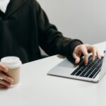 person in black suit jacket holding white ceramic mug