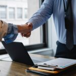 crop colleagues shaking hands in office