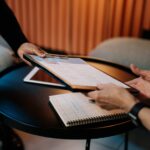 person in black long sleeve shirt writing on white paper