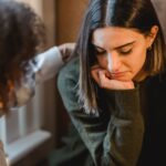 crop woman tapping shoulder of frustrated female friend